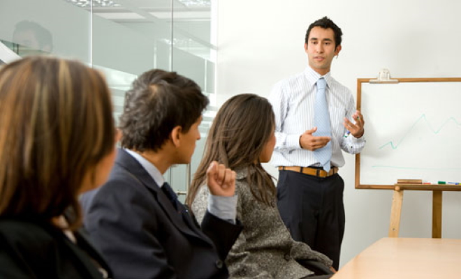 businessman giving demonstration to three people in meeting